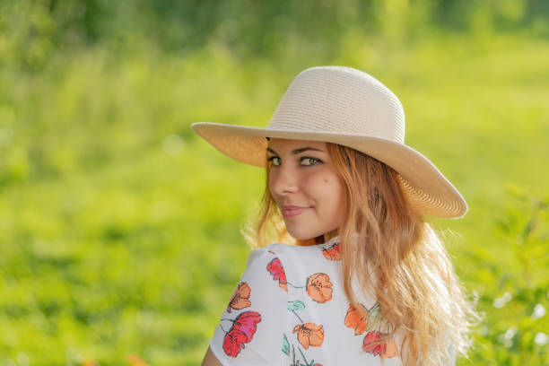 Portrait of attractive  young woman in straw hat looking over the shoulder looking at the camera.