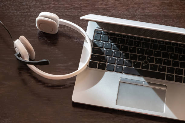 istock Headset on a laptop, wooden table. Call center, home office, customer support, help desk 1403862461