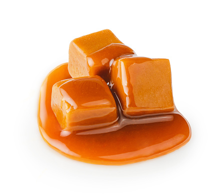 Caramel cubes with caramel sauce isolated on white background.