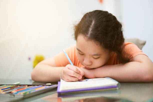 istock cute asia little young girl is writing book 1403863721