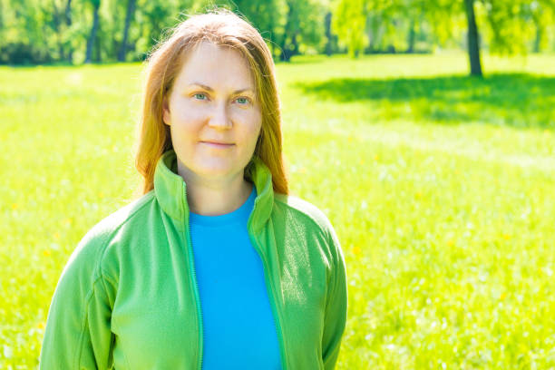 Pretty young woman with red hair in green sunny park