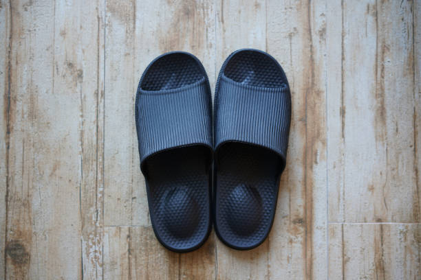 black slide sandals on wooden floor stock photo