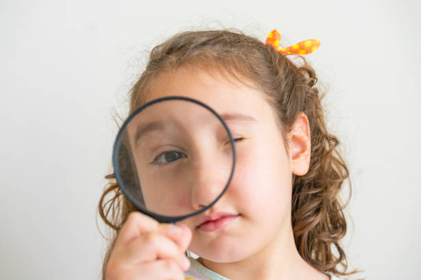 istock Little girl looking through a magnifying glass 1403866286