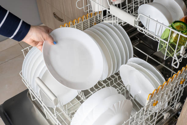 istock A woman's hand takes out a clean white plate from the dishwasher. Modern kitchen with built-in appliances. Multi-colored glasses, white plates and mugs in the dishwasher. 1403870207