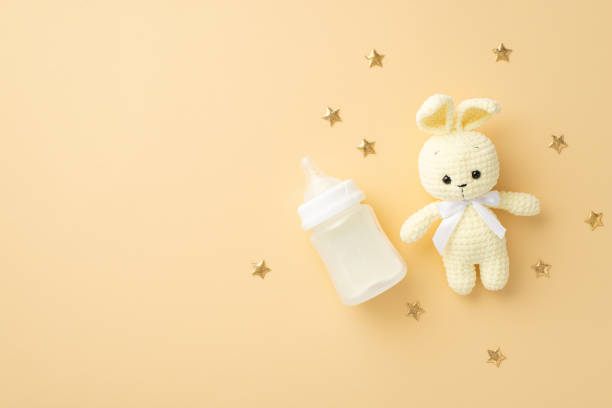 Baby accessories concept. Top view photo of knitted bunny toy milk bottle and gold stars on isolated pastel beige background with copyspace Baby accessories concept. Top view photo of knitted bunny toy milk bottle and gold stars on isolated pastel beige background with copyspace baby shower stock pictures, royalty-free photos & images