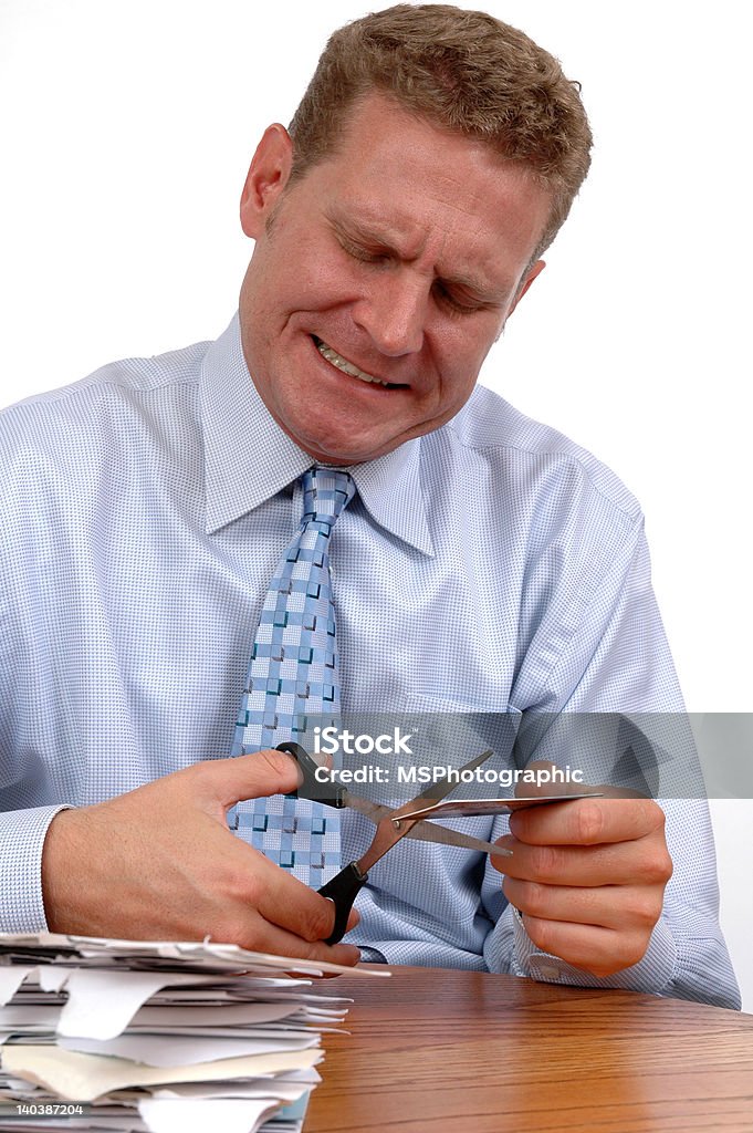 Painful Debt A man behind a pile of bills cutting up a credit card Adult Stock Photo