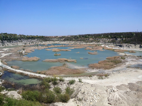 Small small swampy lake on the site of a flooded quarry, with dry shores