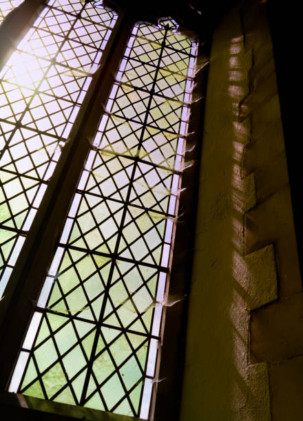 Layers of sunlit cobwebs on the side of an old rural church window in Suffolk, Eastern England.