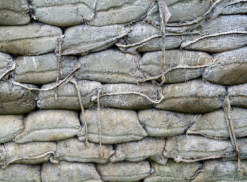 A wall built from weathered sandbags filled with cement which has hardened to make a solid structure.