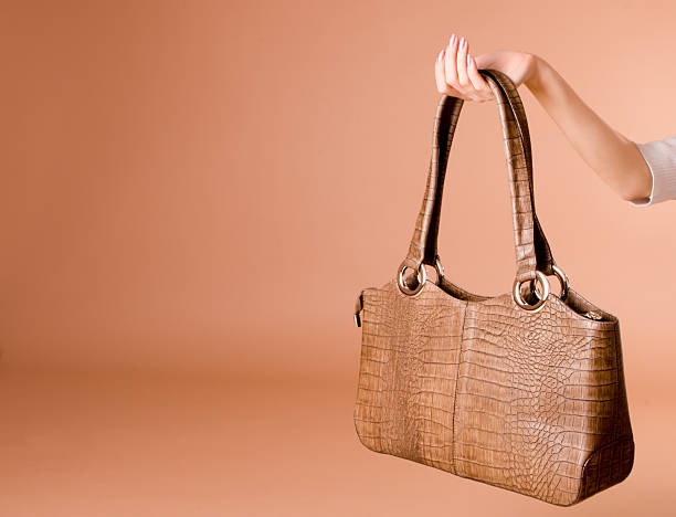 istock Hand holding leather handbag on the beige background 140387745