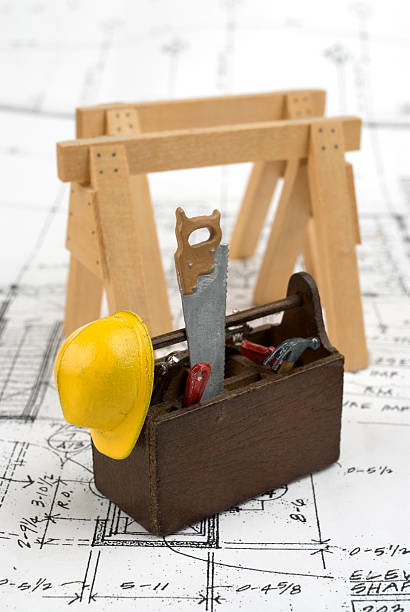 Miniaiture tools on house plans. Closeup image of miniature carpentry tools resting on a set of house plans. sawhorse stock pictures, royalty-free photos & images