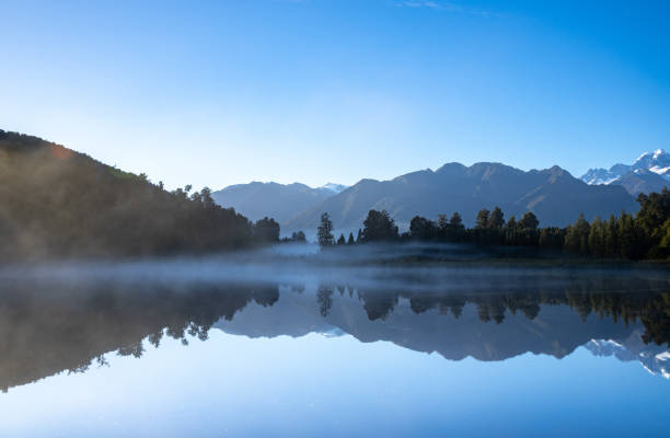 istock Perfect reflection in Lake Matheson surrounded by beautiful natural forest under blue sky 1403879202