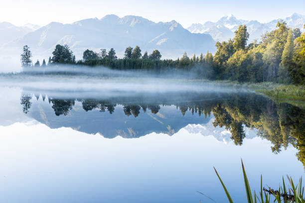 istock Perfect reflection in Lake Matheson surrounded by beautiful natural forest under blue sky 1403879264
