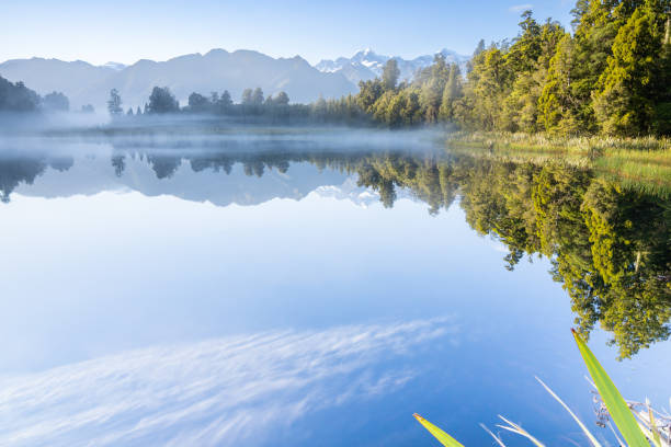 istock Perfect reflection in Lake Matheson surrounded by beautiful natural forest under blue sky 1403879856