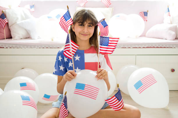 beautiful little girl with long brown hair with american flag balloon - child flag fourth of july little girls imagens e fotografias de stock