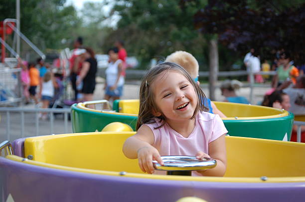 Tea Cups Four year old girl riding the tea cups at an amusement park. fairground ride stock pictures, royalty-free photos & images