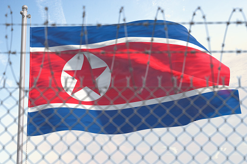 Bandera del norte de Corea detrás de una cerca de alambre de púas. Concepto de sanciones, embargo, dictadura, discriminación y violación de los derechos humanos y la libertad en Corea del Norte. photo