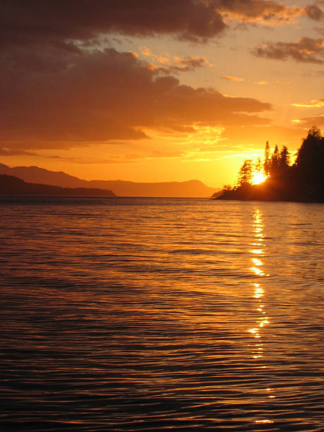 Sunset Over West Coast of British Columbia The Sunshine Coast of British Columbia, Canada, lives up to its name on this gorgeous summer evening. Off in the distance are Thormanby and Texada Islands.  tidal inlet stock pictures, royalty-free photos & images