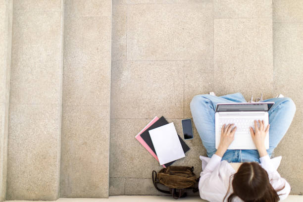 istock Female student is using laptop in front of university building 1403885202