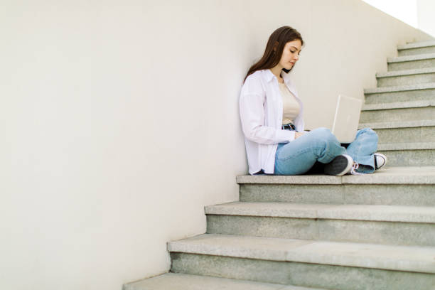 istock Female student is using laptop in front of university building 1403885311