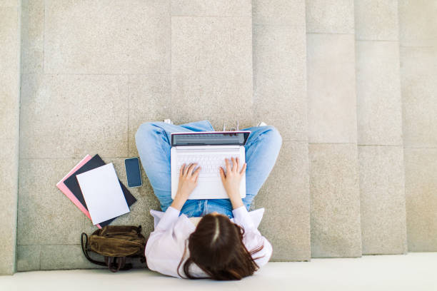 istock Female student is using laptop in front of university building 1403885324