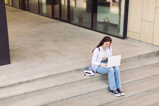 istock Female student is using laptop in front of university building 1403885515
