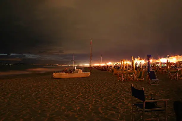 This photo was taken in September 2005 at the beach of Via Reggio, Italy. It shows a lonely paddle-boat on the beach in a warm night.