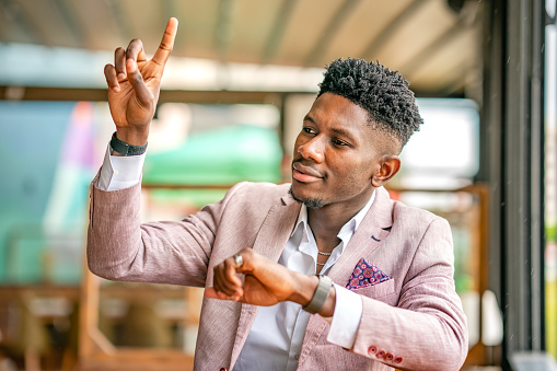 Ivorian Black Businessman raising his hand for calling the waitress
