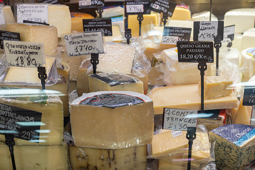 Different types of cheeses in a delicatessen with signs in spanish.