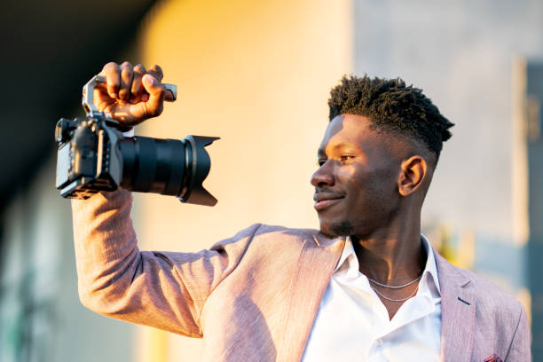 joven camarógrafo sosteniendo una cámara y filmándose a sí mismo - using laptop contemplation accessibility contemporary fotografías e imágenes de stock