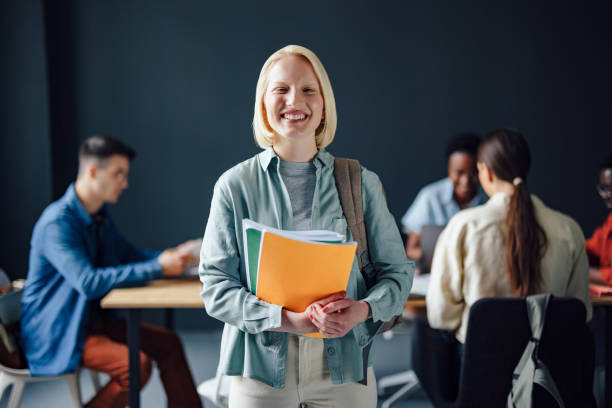istock Portrait Of Smiling Female Student Holding Notebooks While Standing In The Library 1403897442