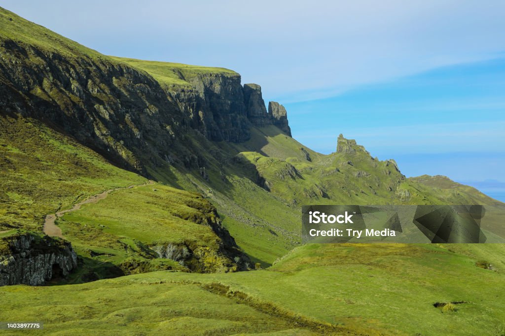 Dramatic cliff and green landscape of the Quiraing in Isle of Skye Hiking trail through the dramatic green cliffs and rock formations of the Quiraing in the Isle of Skye Scotland Quiraing Needle Stock Photo