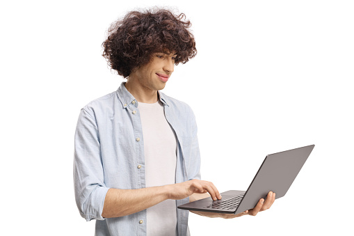 Guy with a curly hair standing and working on a laptop computer isolated on white background