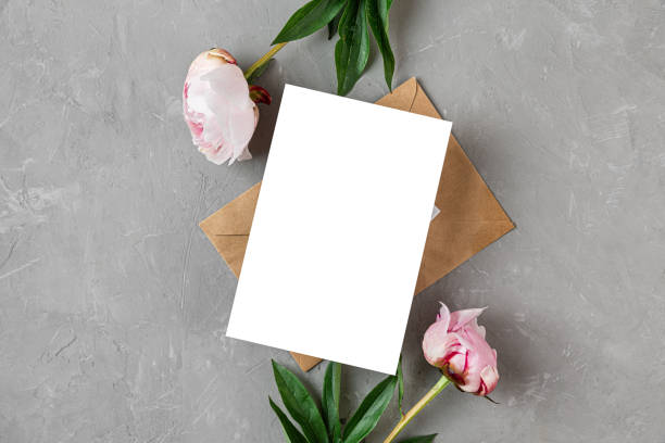 istock Blank greeting card or wedding invitation with pink peony flowers and envelope on gray background. Mock up 1403900509