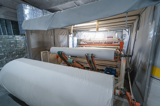 Toilet paper production. Machine with a large roll of recycled paper.