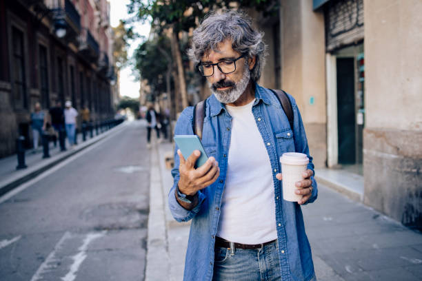 Portrait of a mature tourist texting and drinking coffee on the move stock photo
