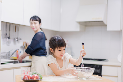 A girl and her mother helping with the cooking