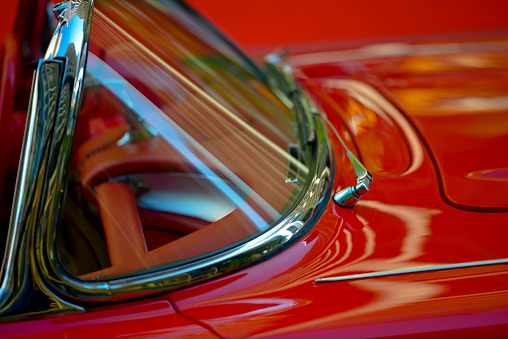 Close up of red classic car and chrome door handle.