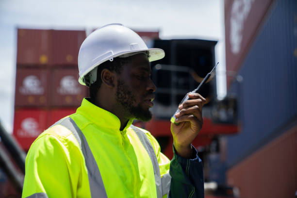 istock African American working engineer foreman radio control in port cargo shipping container yard. 1403926998