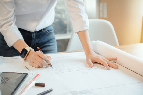 istock Selective focus, Asian female architect or engineer Drawing the design of the building structure in the blueprint. Asian female architect or engineer Sit and analyze, design projects in the office. 1403932191