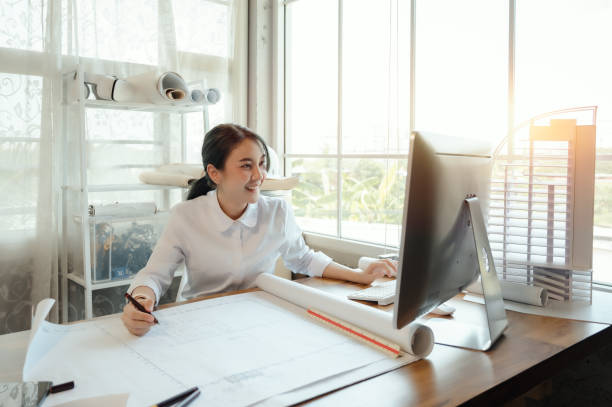istock Selective focus, Asian female architect or engineer Drawing the design of the building structure in the blueprint. Asian female architect or engineer Sit and analyze, design projects in the office. 1403932192