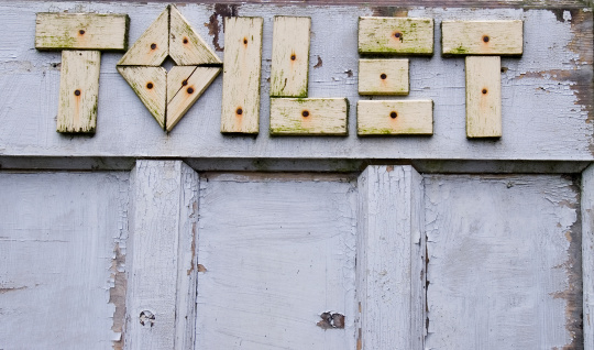 wooden letters spelling out toilet on old door