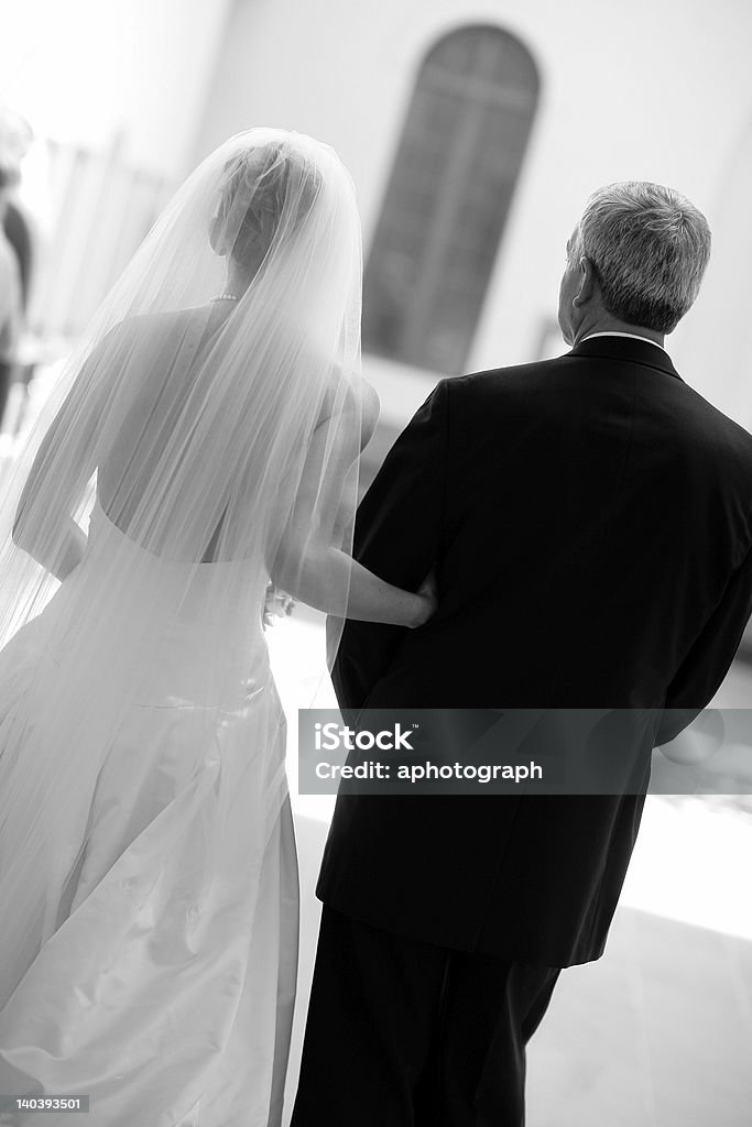 Black and white image of bride and father from behind A bride and her father walking down the aisle. Father Stock Photo