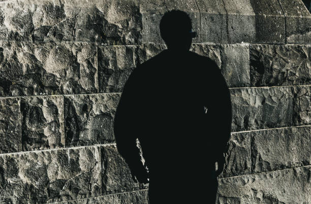 A mysterious silhouette of a person against a rough rock wall texture