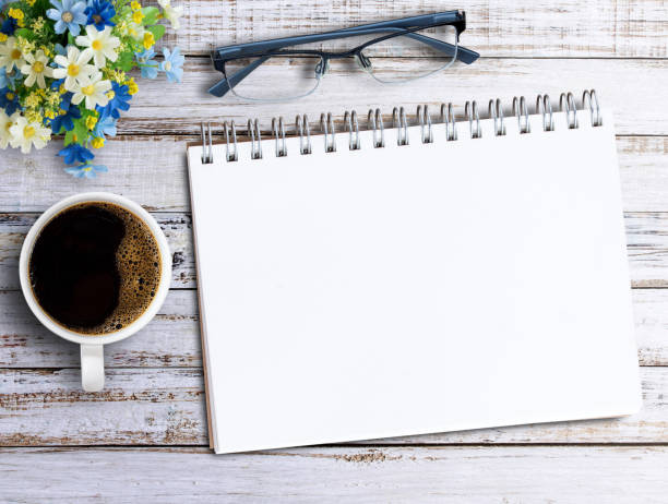 istock Top view with blank notebook and coffee on wood table in office workplace. 1403937503