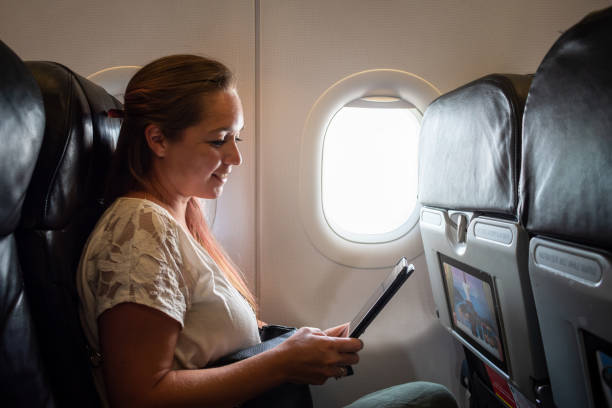 istock Young woman reading a book on the plane. 1403937504