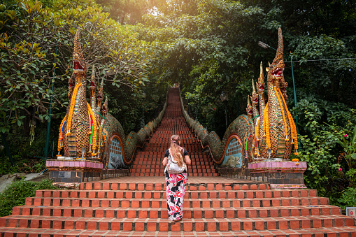 Young woman walking up the stairs of the temple, Doi Suthep in Chiang Mai, Thailand. Huge stairs of Doi Suthep temple in Chiang Mai, Thailand