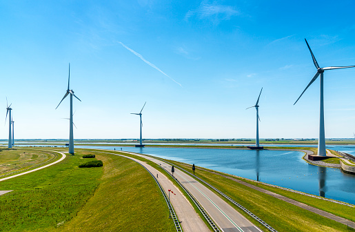 An empty dutch  road and a row of wind turbines. Summer  day in Zeeland, the Netherlands