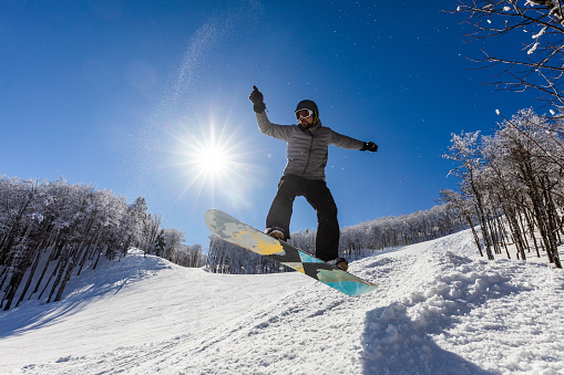 Low angle view of a man jumping with snowboard on a mountain. Copy space.