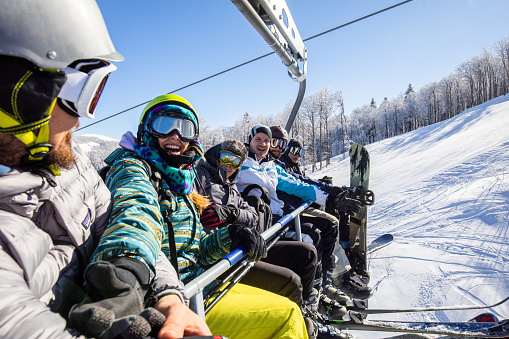 Group of happy friends taking a selfie while driving on a ski lift in winter day.
